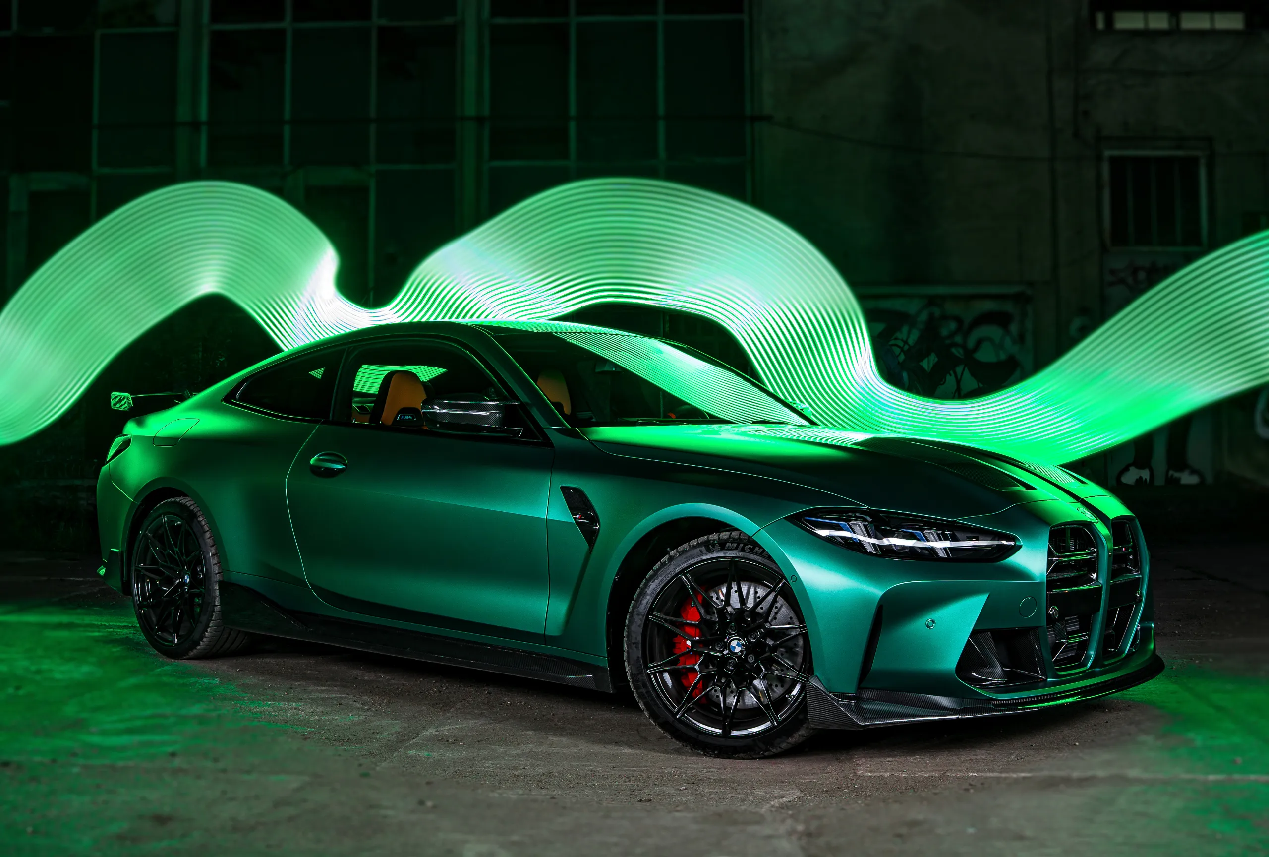 Zaparkowany sportowy samochód w hali z zielonymi neonami w tle.