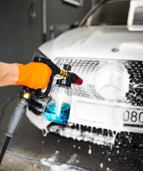 Proces czyszczenia karoserii samochodu pianą z użyciem myjki ciśnieniowej.